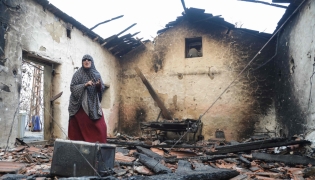 A woman inspects her damaged house after it was burned down in a forest fire in Bordj T'har, a town and commune in Algeria's northeastern Jijel Province, on August 27, 2026. (Photo by AFP)