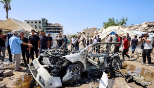 People gather around a destroyed vehicle following an Israeli strike in the Rimal neighbourhood of Gaza City on September 1, 2026. (Photo by Omar AL-QATTAA / AFP)