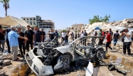 People gather around a destroyed vehicle following an Israeli strike in the Rimal neighbourhood of Gaza City on September 1, 2026. (Photo by Omar AL-QATTAA / AFP)