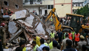 Bulldozers clear debris as rescue personnel conduct a search operation at the site following a building collapse in the Satya Niketan area in New Delhi on September 6, 2026. (Photo by Sajjad HUSSAIN / AFP)