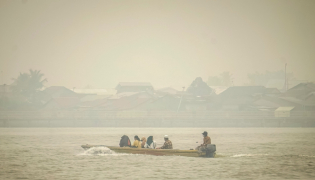People travel on a river boat as thick haze from forest and land fires blankets Benua Melayu Darat village in Pontianak, West Kalimantan, on September 16, 2026. (Photo by DITO / AFP)