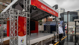 A man wearing a rain jacket stands in front of a booth promoting the 2026 Asian Games in Nagoya, Aichi Prefecture on September 16, 2026. (Photo by Mohd Rasfan / AFP)