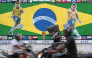 Motorcyclists ride past a graffiti featuring Brazilian football player Neymar (L) and Raphinha ahead of a FIFA international friendly football match between India and Brazil in Kolkata on September 29, 2026. (Photo by Dibyangshu Sarkar / AFP)
