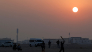 Foreign workers play cricket at sunset in Doha on October 1, 2026. (Photo by KARIM JAAFAR / AFP)
