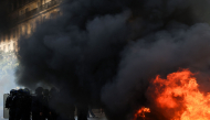 Police officers stand guard by bins and furniture set on fire in the street during a demonstration of high-school students, in Paris on October 6, 2026, as part of a nationwide protest movement over learning conditions. (Photo by Kenzo TRIBOUILLARD / AFP)

