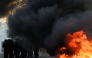 Police officers stand guard by bins and furniture set on fire in the street during a demonstration of high-school students, in Paris on October 6, 2026, as part of a nationwide protest movement over learning conditions. (Photo by Kenzo TRIBOUILLARD / AFP)
