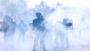 Police officers stand in the smoke during a demonstration of high-school students, in Paris on October 6, 2026, as part of a nationwide protest movement over learning conditions. (Photo by Kenzo TRIBOUILLARD / AFP)