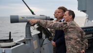 This handout photograph released and taken by the French Ministry of the Armed Forces and Veterans on October 6, 2026 shows French President Emmanuel Macron (L) attending the first test launch of a new intercontinental missile, fired from a nuclear-powered ballistic missile submarine off the coast of Finistere, western France, on October 6, 2026. (Photo by Benjamin PAPIN / French Ministry of the Armed Forces and Veterans / AFP) 