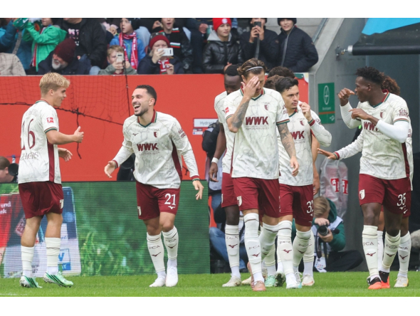 Augsburg's German midfielder #19 Robin Fellhauer (hidden) celebrates scoring the opening goal with his teammates during the German first division Bundesliga football match. (Photo by Karl-Josef HILDENBRAND / AFP) 