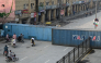 Commuters gather at a road blocked with shipping containers amid ongoing protests by the opposition Pakistan Tehreek-e-Insaf (PTI) party demanding the release of jailed former prime minister Imran Khan in Peshawar on October 11, 2026. (Photo by Abdul Majeed / AFP)