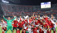 This picture taken on October 3, 2026 shows South Korean players celebrating after winning the gold medal in the men's football final match between Japan and South Korea in the 2026 Asian Games at Toyota Stadium in Toyota. (Photo by YONHAP / AFP) 