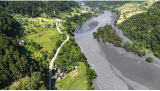 An aerial view shows muddy water flowing through the Budhi Gandaki river, separating Nepal's Gorkha (L) and Dhading districts on October 14, 2026, in the aftermath of a flash flood caused by a dry landslide. (Photo by Prakash Mathema / AFP)