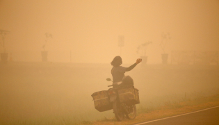 A person takes photos amid thick haze caused by forest and peatland fires in Palangka Raya, Central Kalimantan, Indonesia, Oct. 13, 2026. (Photo by Regina Safri/Xinhua)