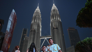 People walk past the Petronas Tower in Kuala Lumpur on October 18, 2026. (Photo by Jam STA ROSA / AFP)