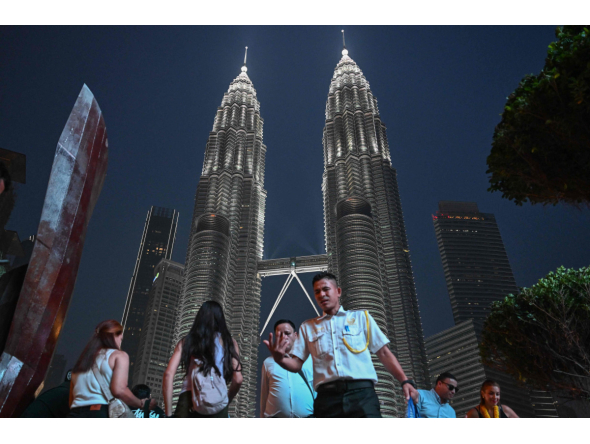 People walk past the Petronas Tower in Kuala Lumpur on October 18, 2026. (Photo by Jam STA ROSA / AFP)