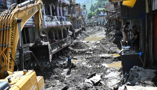 A man operates a backhoe to clean a street in the aftermath of flash floods at Devighat in Nepal's Nuwakot district on September 8, 2026. Photo by Pedro PARDO / AFP