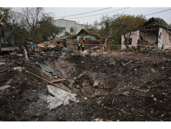 Ukrainian police officers stand next to a crater at the site of a missile strike in Kyiv on October 22, 2026. (Photo by Serhii DILIN / AFP)