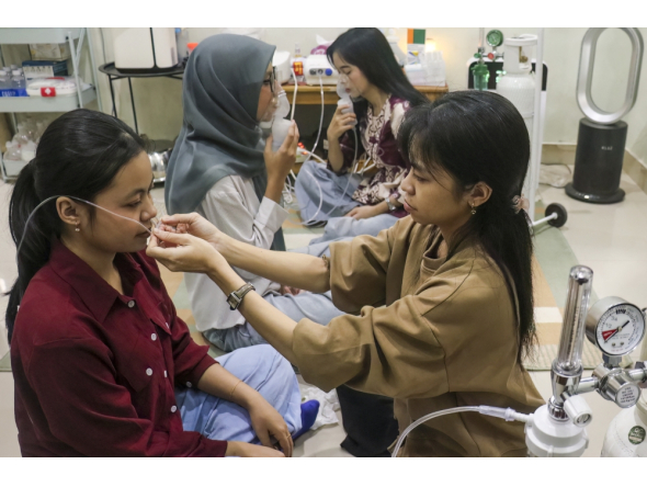 A volunteer (R) assists a woman with a nasal oxygen cannula at a shelter to aid residents experiencing respiratory difficulties in Palangkaraya, Central Kalimantan province on October 26, 2026. Photo by REINA / AFP