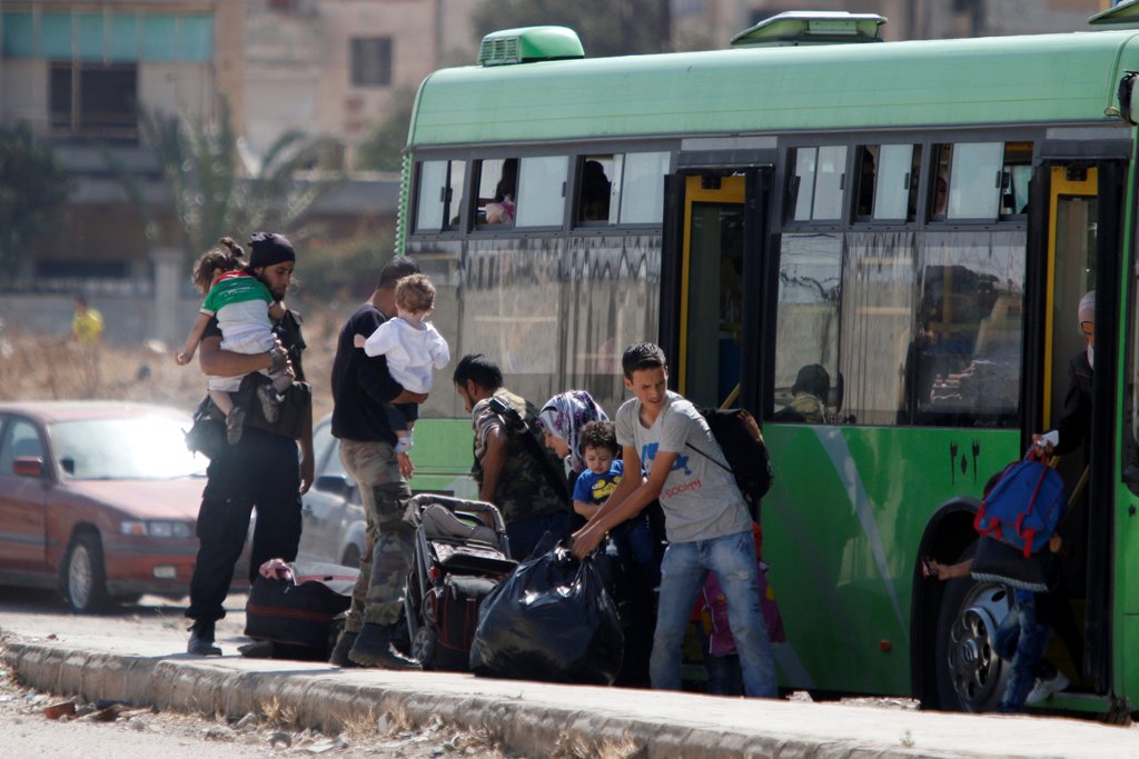 Syrian rebels and their families carry their luggage into a bus to evacuate the besieged Waer district in the central Syrian city of Homs, after a local agreement reached between rebels and Syria's army, Syria September 22, 2016. REUTERS/Omar Sanadiki 