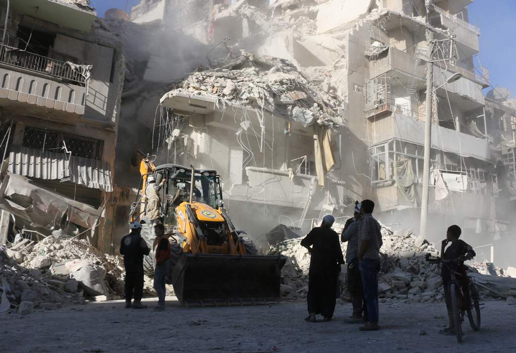 Civilians watch as a tractor clears the rubble following Syrian government forces airstrikes in the rebel held neighbourhood of Tariq a-Bab in Aleppo on September 24, 2016. AFP / THAER MOHAMMED
