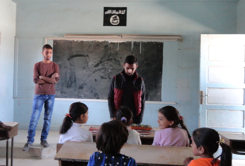 Syrian children sit at a classroom adorned with an Islamic State group insignia on the first day of classes in the Syrian town of Manbij on September 25, 2016.  AFP / Ayham al-Mohammad