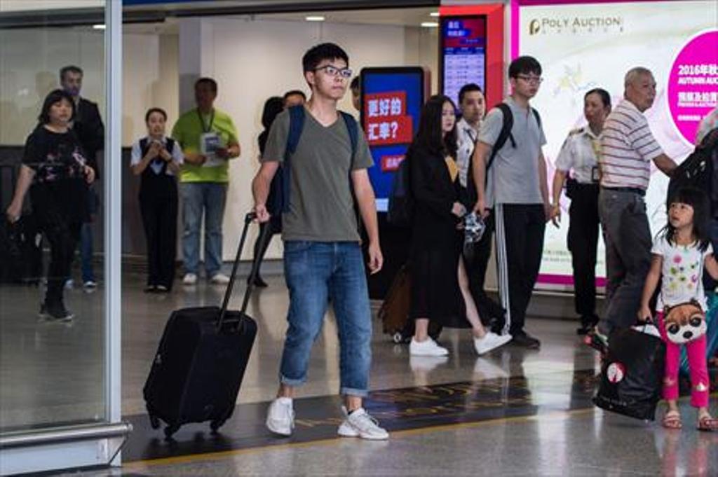Hong Kong democracy campaigner Joshua Wong (centre L) steps into the arrivals hall at the international airport in Hong Kong on October 5, 2016, after being deported from junta-run Thailand.  / AFP / ANTHONY WALLACE
