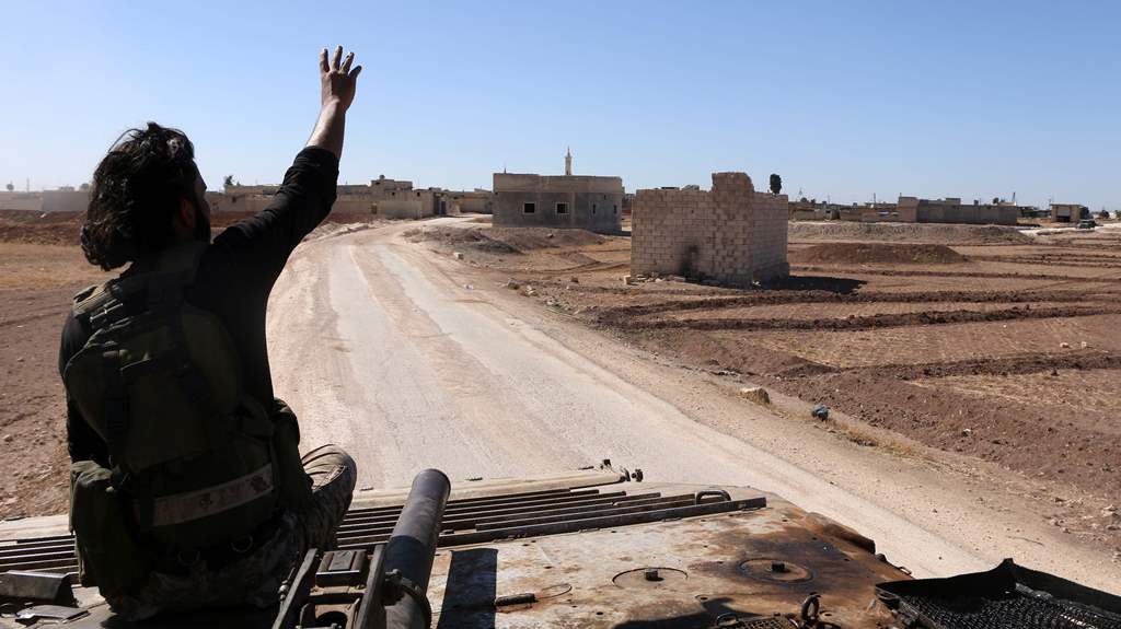 A rebel fighter gestures as he sits atop an armoured vehicle as they enter the village of Tilalayn on the western outskirts of the northern Syrian town of Dabiq, on October 16, 2016. AFP / Nazeer al-Khatib