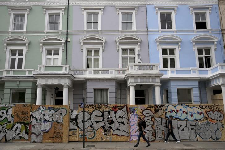 People walk past boarded-up houses ahead of the Notting Hill Carnival in London, Britain, August 27, 2016. (REUTERS / Neil Hall) 
