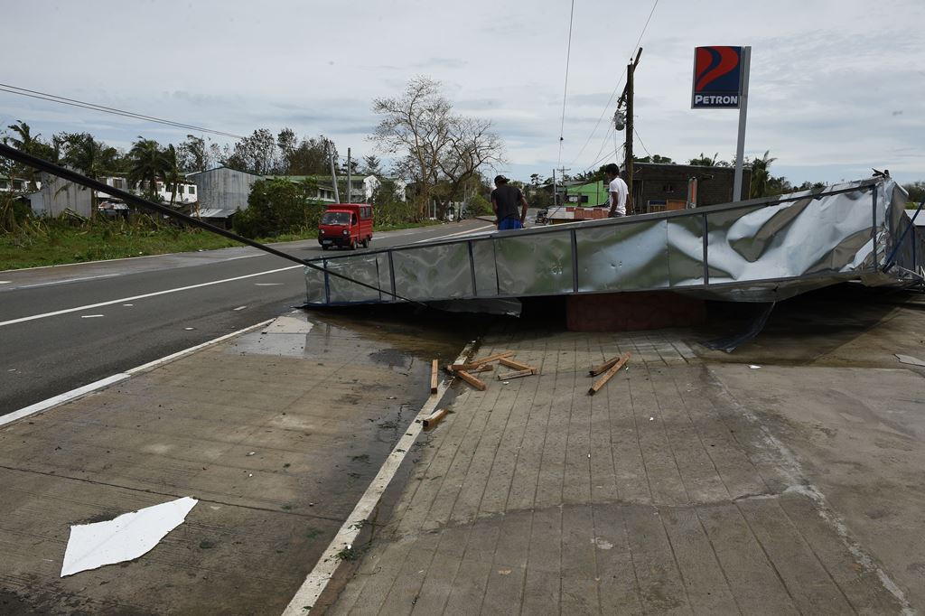 Workers dismantle a damaged roof blown away at the height of typhoon Haima along a highway in Ilagan town, Isabela province, north of Manila on October 20, 2016. AFP / TED ALJIBE