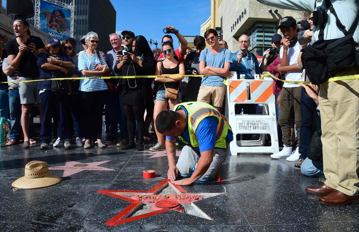 This file photo taken on October 26, 2016 shows a crowd as it gathers to watch as Donald Trump's vandalized Star along the Hollywood Walk of Fame is repaired before being replaced on October 26, 2016 in Hollywood, California. (AFP / Frederic J. BROWN)
