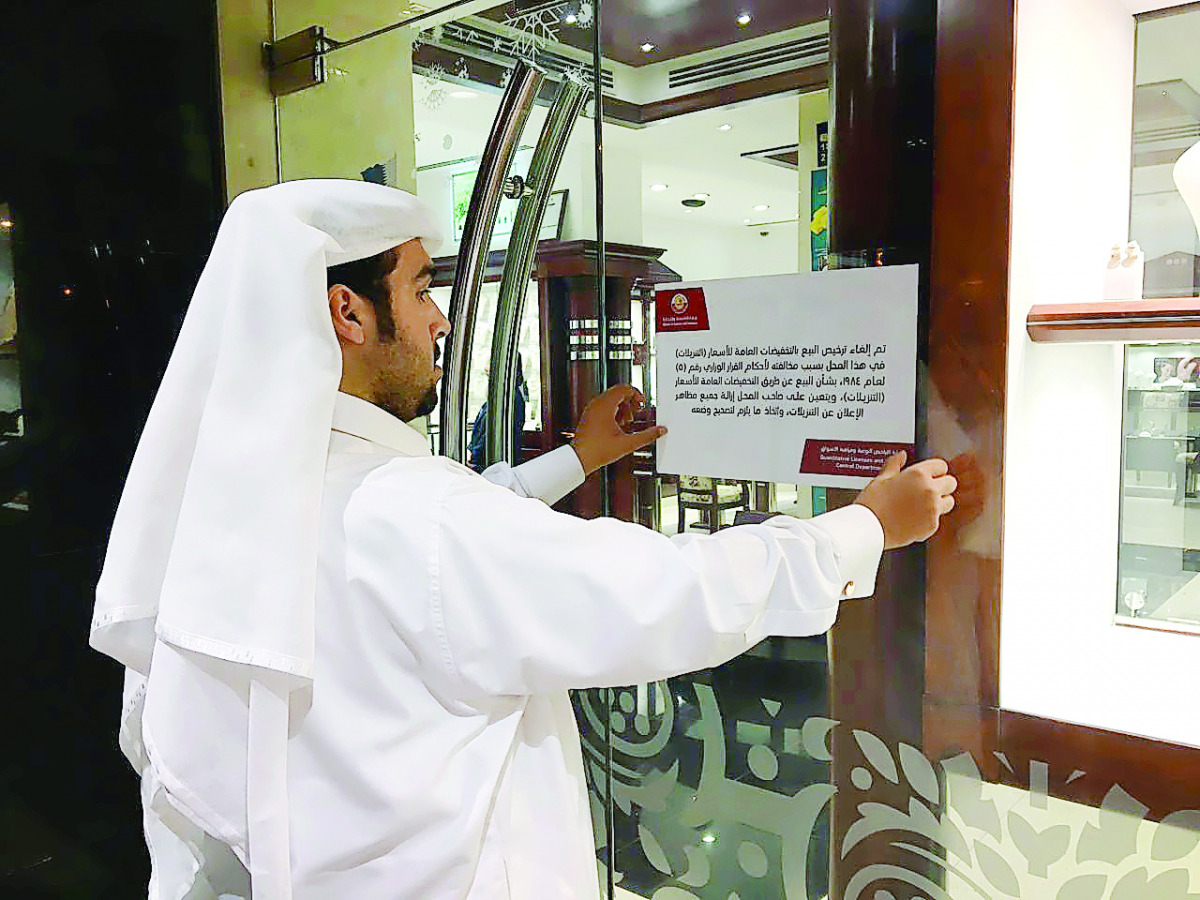 A Ministry official putting up a notice announcing the cancellation of the licence for promotion at a jewellery shop.