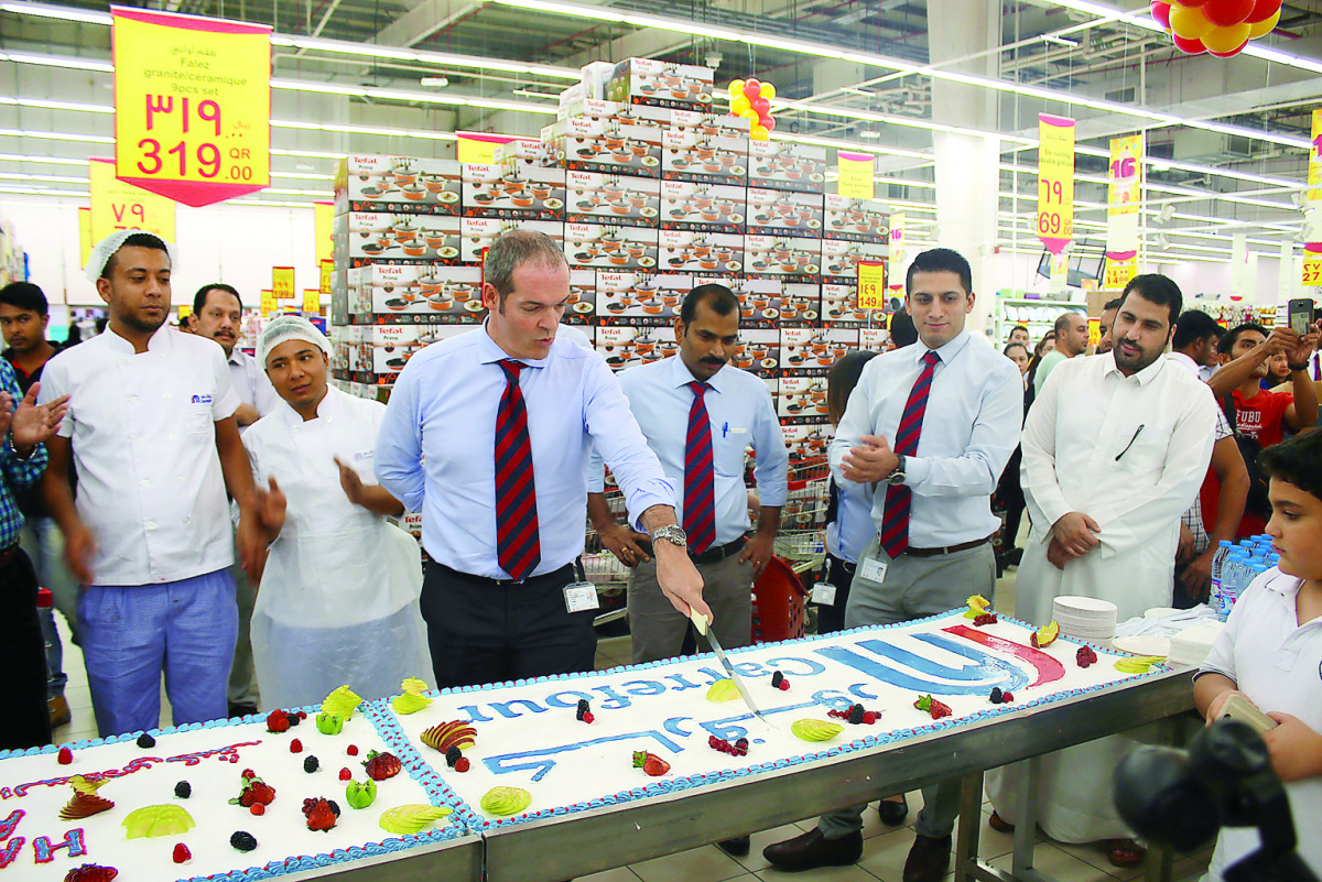 A cake being cut to celebrate Carrefour Qatar's 16th anniversary.