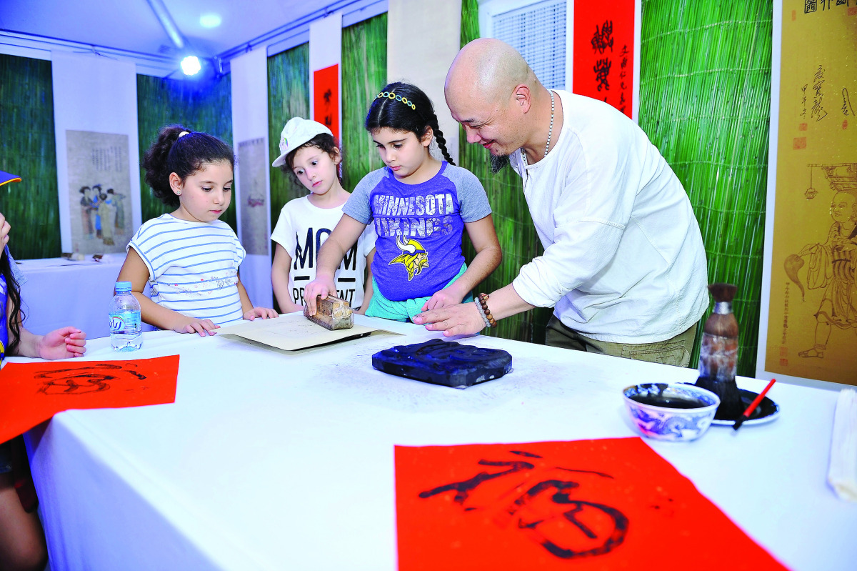 A Chinese artist demonstrates to children the ancient art of woodblock printing at the bazaar.  Pic: Baher Amin / The Peninsula