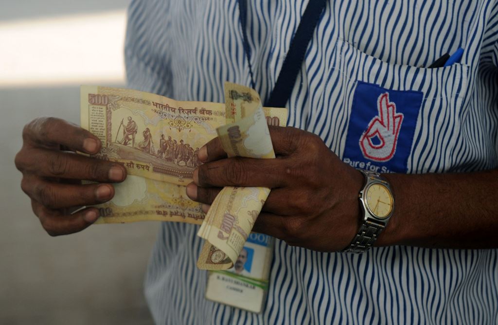 An Indian worker holds a stack of 500 Indian Rupee notes on the forecourt of a fuel station in Chennai on November 9, 2016. AFP / ARUN SANKAR
