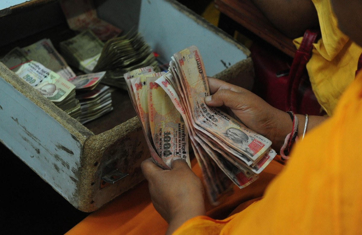An Indian railway counter cashier counts 1000 and 500 rupee notes at Allahabad Railway station in Allahabad on November 9, 2016. India's government tried to quell the panic caused by a bombshell decision to withdraw 500 and 1,000 rupee notes from circulat
