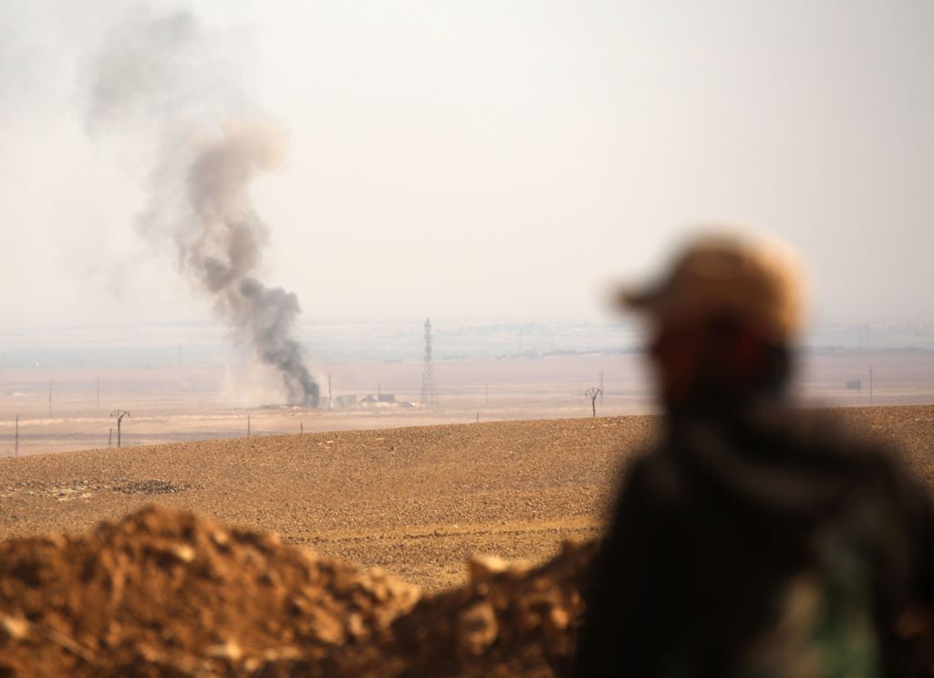 Smoke billows in the background as a member of the Syrian Democratic Forces (SDF), a US-backed Kurdish-Arab alliance, looks on in the village of Tal Aaj, 5 kilometre from the Syrian town of Ain Issa, some 50 kilometres (30 miles) north of Raqa, on Novembe