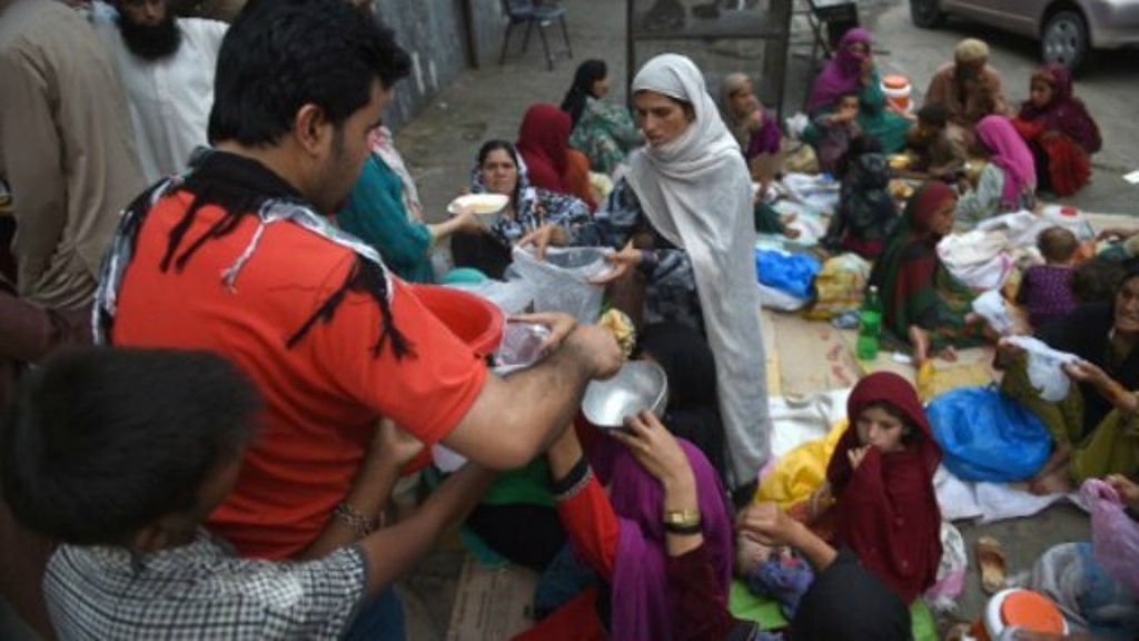 A Pakistani man distributes rice to Afghan refugees gathered outside a food distribution center before breaking their fast during the Muslim holy month of Ramadan in Islamabad on June 20, 2016. (AFP)