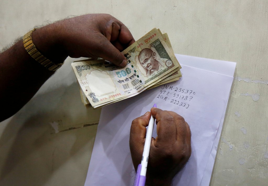 A man writes the serial numbers of 500 Indian rupee banknotes on the back of a form before depositing them in a bank in Kolkata, India, November 13, 2016. REUTERS/Rupak De Chowdhuri
