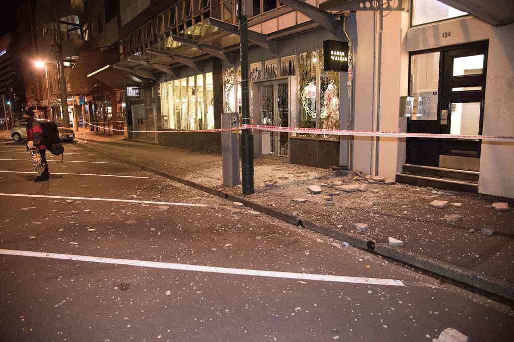Debris from fallen concrete off buildings are seen on a sidewalk past a cordon line in Wellington early on November 14, 2016 following an earthquake centred some 90 kilometres (57 miles) north of New Zealand's South Island city of Christchurch. AFP / Mart