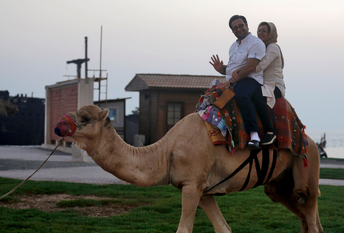 Iranian tourists ride a camel in Iran's southern resort island of Kish on November 1, 2016. Iranian investors are pouring money into Kish island in the Gulf, hoping its white sand beaches, coral reefs and more relaxed Islamic rules, could make it a major 