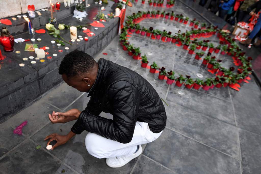 A man puts a candle near a peace symbol made with flowers on place de la Republique in Paris on November 13, 2016 as France marked the first anniversary of the Paris attacks with sombre ceremonies and painful memories for the relatives of the 130 people k