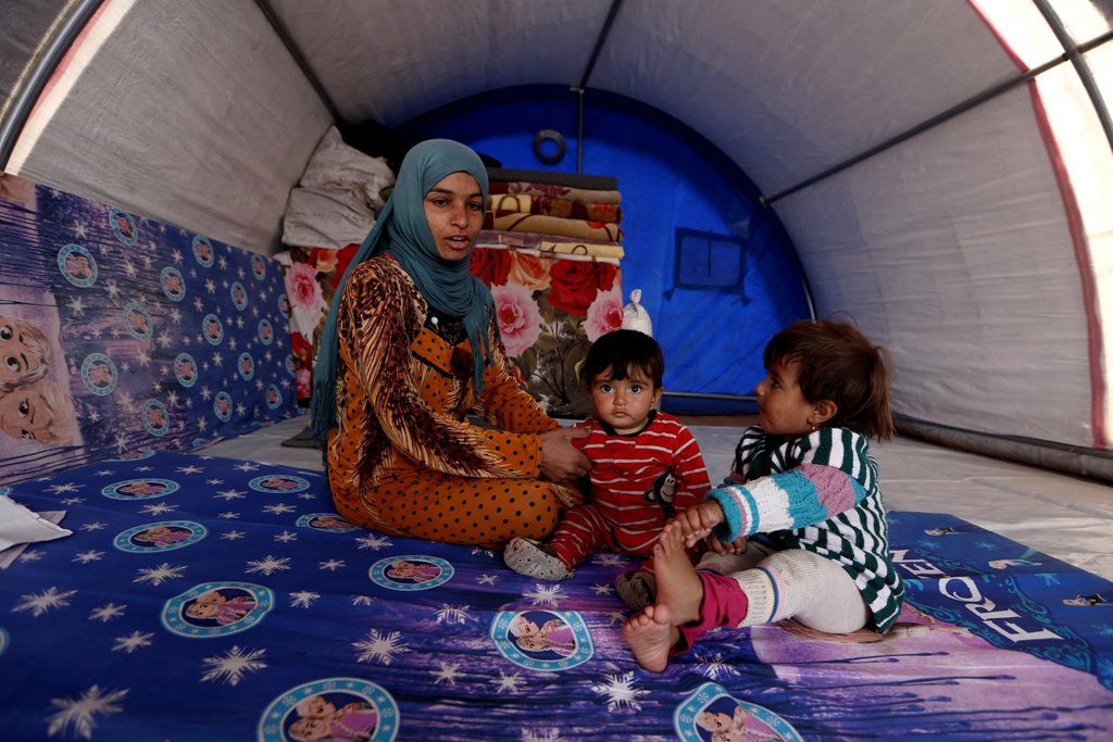 A woman who fled from Mosul sits with her daughters Nada, 8 months old, and Houda (R), 2, who were both born under Islamic State rule and have no identity documents recognised by Iraqi authorities, inside their tent in Khazer refugee camp, Iraq November 1