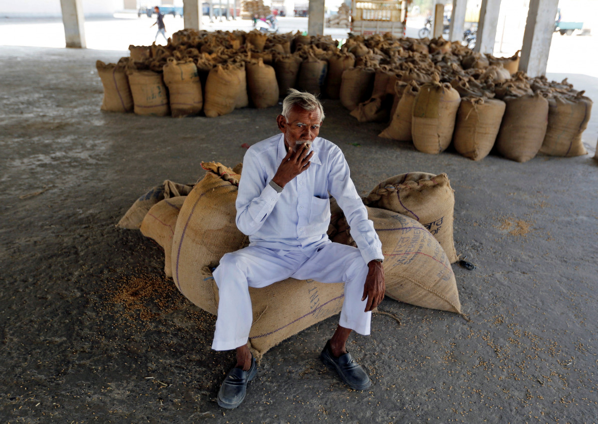 A farmer smokes while sitting on sacks of paddy crops as he waits for customers, one week after the Indian government withdrew the circulation of high denomination banknotes, in Sanand village on the outskirts of Ahmedabad, India, November 15, 2016. REUTE