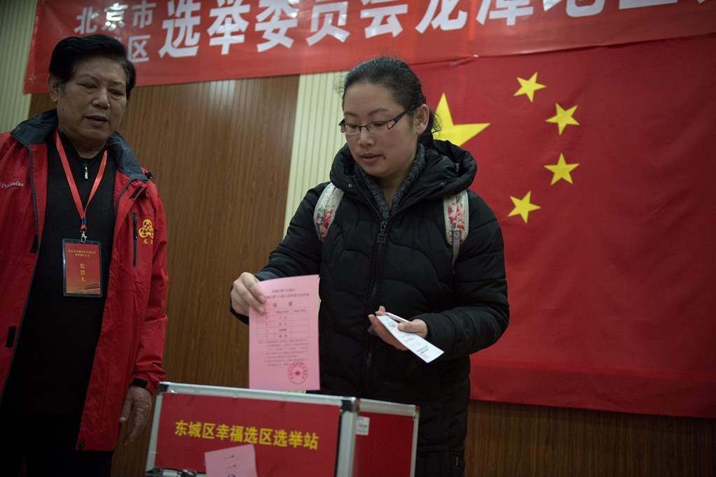 In this picture taken on November 15, 2016, a woman casts her vote at a polling station in Beijing. AFP / NICOLAS ASFOURI 