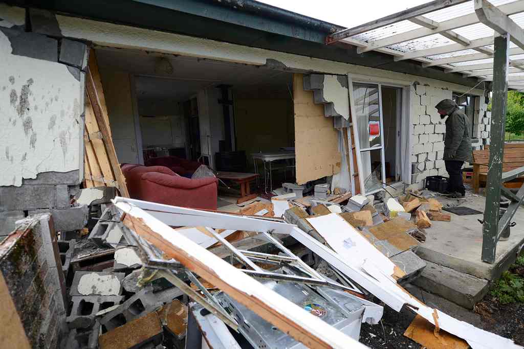 A man looks at damage to a house in Waiau town, some 80 kms to the south of Kaikoura, on November 16, 2016, after an earthquake hit New Zealand just after midnight on Monday. AFP / Matias Delacroix