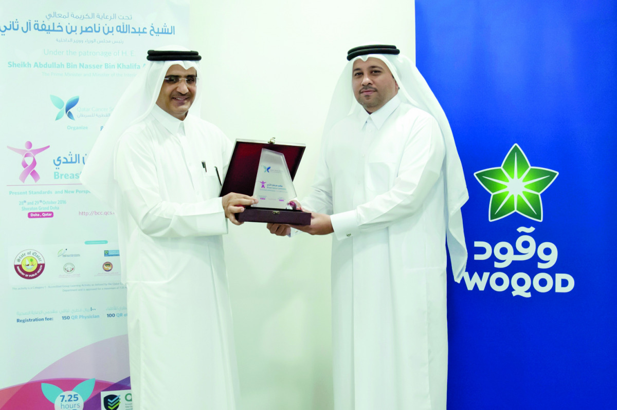 Eng Fahad Abdullah Al Subaiey, Chief Marketing Officer at Woqod, being presented with a commemorative plaque by a Qatar Cancer Society official.