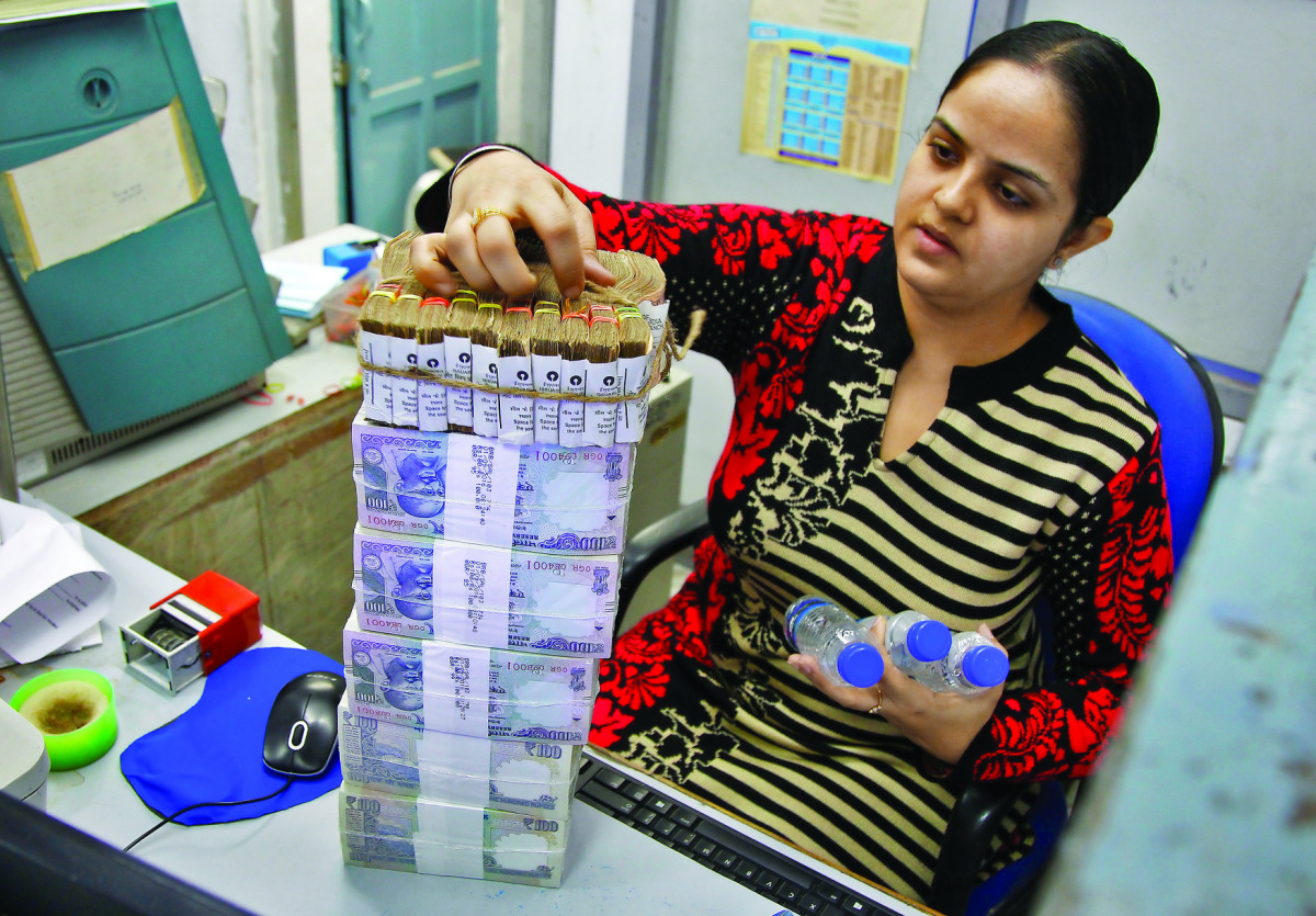 A cashier stacks Indian currency notes inside a bank in Chandigarh, India.