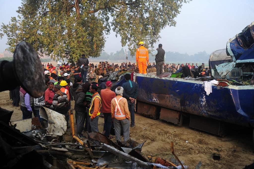 Rescue worker and onlookers stand near the wreckage of the train on the damaged tracks where a train derailed near Pukhrayan in India's Kanpur district on November 21, 2016. AFP / SANJAY KANOJIA