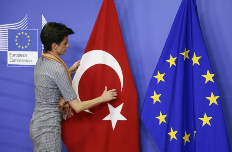Filephoto of a woman adjusting the Turkish flag next to the European Union flag at the EU Commission. Reuters 
