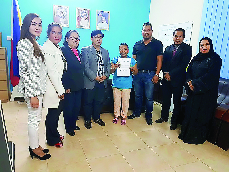 Andrea Baggayan (fifth left), the first beneficiary of 'Send Someone Home' programme, receives her ticket and pocket money at POLO-OWWA office. Also seen are Philippine Labour Attache David Des Dicang (fourth left), UFOQ Chairman Ressie S Fos (second righ